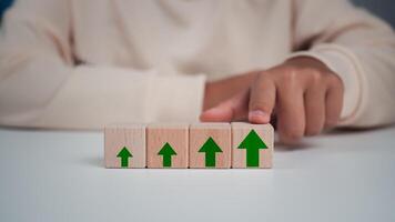 Businessman taps his finger on his wooden block with green arrow print for the future growth plan of his organization. finance, management, plan, management, strategy, photo