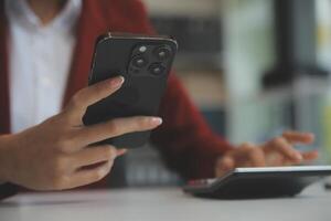 Asian businesswoman in formal suit in office happy and cheerful during using smartphone and working photo