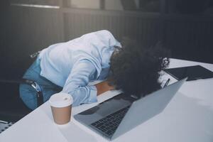 Sad tired young asian lady thinking, sleep at laptop, suffering from overwork, stress in room interior. Deadline, problems in study, work, business, freelance at home new normal with tech photo