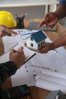 Engineers are consulting the team to design an architectural structure for clients with blueprints and building models to work at office. photo