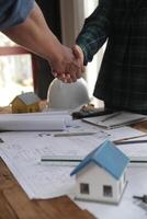 ingeniero y contratista unirse manos después firma contrato, ellos son teniendo un moderno edificio proyecto juntos. exitoso cooperación equipo concepto foto