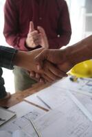 ingeniero y contratista unirse manos después firma contrato, ellos son teniendo un moderno edificio proyecto juntos. exitoso cooperación equipo concepto foto