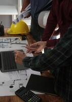 ingenieros son consultante el equipo a diseño un arquitectónico estructura para clientela con planos y edificio modelos a trabajo a oficina. foto