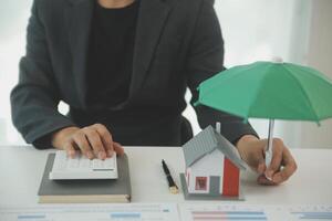 Businessmen holding pens, signing home titles with insurance, care about real estate services and the idea of real estate agents offering interest in installments to their customers. photo