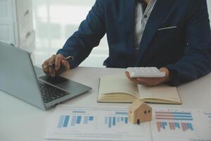 Businessmen holding pens, signing home titles with insurance, care about real estate services and the idea of real estate agents offering interest in installments to their customers. photo