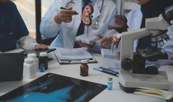 médico, reunión y ordenador portátil para equipo en oficina en discusión, lluvia de ideas y planificación. doctor, enfermero y computadora en escritorio, trabajo en equipo o taller para modelo interno Organo. foto