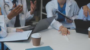 Team of medical staff having morning meeting in boardroom. Doctors and nurses looking at digital tablet. photo