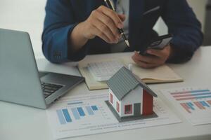 Businessmen holding pens, signing home titles with insurance, care about real estate services and the idea of real estate agents offering interest in installments to their customers. photo