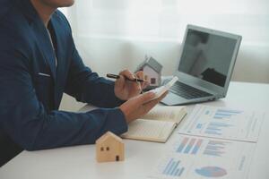 Businessmen holding pens, signing home titles with insurance, care about real estate services and the idea of real estate agents offering interest in installments to their customers. photo