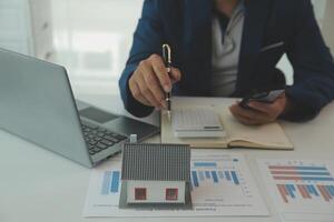 Businessmen holding pens, signing home titles with insurance, care about real estate services and the idea of real estate agents offering interest in installments to their customers. photo