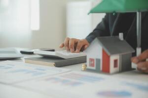 Businessmen holding pens, signing home titles with insurance, care about real estate services and the idea of real estate agents offering interest in installments to their customers. photo