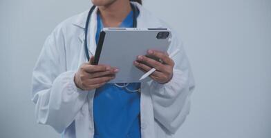 Woman doctor using tablet computer while standing straight in hospital photo