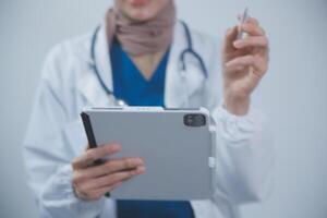 Doctor wearing white coat and watching patient data in Tablet . photo