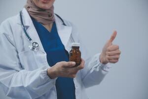 Southeast Asian medical doctor holding a bottle of pills, smiling isolated white background photo