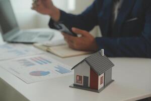 Businessmen holding pens, signing home titles with insurance, care about real estate services and the idea of real estate agents offering interest in installments to their customers. photo