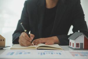 Businessmen holding pens, signing home titles with insurance, care about real estate services and the idea of real estate agents offering interest in installments to their customers. photo