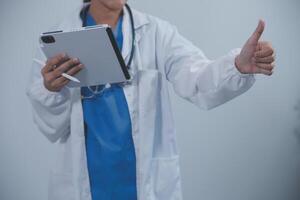 Woman doctor using tablet computer while standing straight in hospital photo