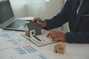 Businessmen holding pens, signing home titles with insurance, care about real estate services and the idea of real estate agents offering interest in installments to their customers. photo