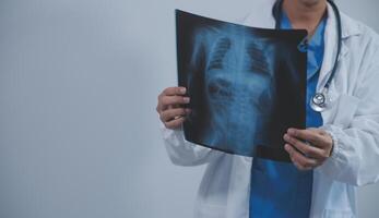 Asian Muslim doctor in hijab and scrubs headphones around her neck Stand confidently in the medical office, isolated on white background, holding x-ray film. photo