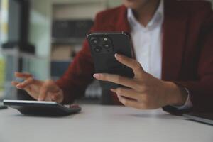 mujer de negocios asiática con traje formal en la oficina feliz y alegre durante el uso del teléfono inteligente y el trabajo foto