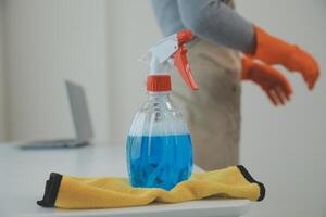 Woman cleaning table using rag and diffuser at home. photo