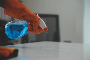 Woman cleaning table using rag and diffuser at home. photo