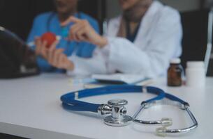 Doctor discussing diagnosis during the meeting. Group of doctor discussing work matter in the office at work. The medical team discusses treatment options with the patient. photo