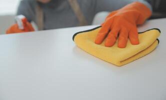 Woman cleaning table using rag and diffuser at home. photo