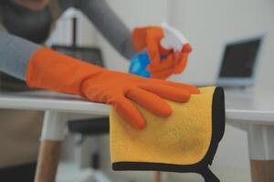 Woman cleaning table using rag and diffuser at home. photo