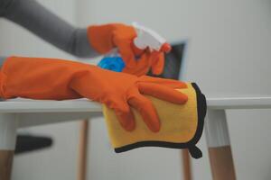 mujer limpieza mesa utilizando trapo y difusor a hogar. foto