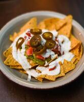 Serving of nachos with white sauce and jalapenos photo