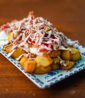 Portion of potatoes with fried eggs and cured Iberian ham. photo