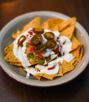 Serving of nachos with white sauce and jalapenos photo