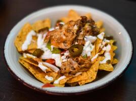 Serving of nachos with meat, cheese, white sauce and jalapenos photo