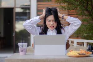 oficina hermosa asiático mujer en al aire libre cafetería. estresado mareado niña hecho un error mientras haciendo trabajo para contenido o publicidad foto