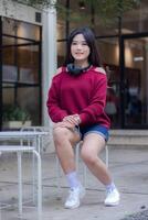 portrait of beautiful sexy asian woman exploring cafe outdoors. girl sitting smiling for product or service promotion photo