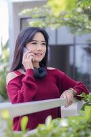 retrato de hermosa sexy asiático mujer explorador café al aire libre. niña sentado sonriente teléfono alguien sincero foto