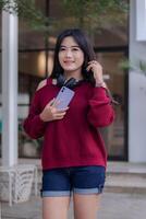 portrait of beautiful sexy asian woman exploring cafe outdoors. girl sitting smiling carrying cellphone for communication photo