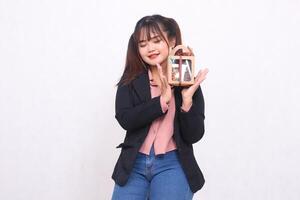 Beautiful Asian girl in her 20s smiling enthusiastically holding up a Christmas gift in the form of a hamper in her hand on a white background for advertising materials, banners, billboards photo