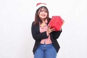 hermosa asiático niña en traje alegre sonrisa con Papa Noel claus sombrero posando con Navidad regalo caja regalo y levantamiento caja y besos en blanco antecedentes para promoción, publicidad, bandera, cartelera foto