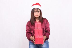 plain beautiful young southeast asian girl carrying 3 boxes gifts at christmas wearing santa claus hat modern red shirt outfit holding all white background for promotion and advertising photo