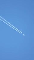 avión a reacción volando alto en el cielo dejando estelas en el cielo azul claro. video