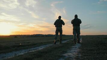 Ucrania soldados patrullando a atardecer, dos soldados caminando a lo largo un rural camino a oscuridad. video