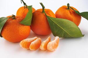 Two ripe tangerines and tangerine slices on a white background. Organic tangerine with green leaf. Mandarin. photo