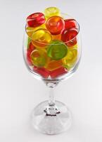 Glass goblet full of beautiful multi-colored candies. Multi-colored candies in a glass goblet. photo