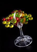 A lot of candy canes are scattered from an overturned glass goblet. Multi-colored candies in a glass on a black background. photo