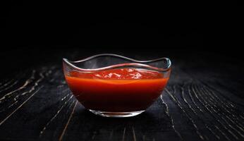 salsa de tomate en un vaso taza en un negro antecedentes. foto