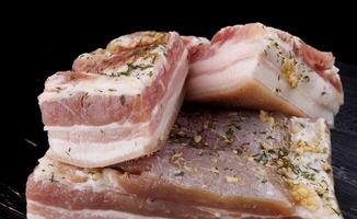 Appetizing salty lard with layers of meat with garlic and herbs. Delicious lard on a wooden cutting board. photo