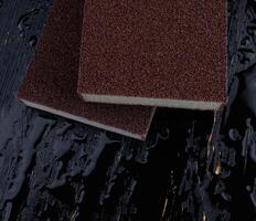 Melamine sponge on a black wet background. Beautiful drops of water around a melamine sponge. photo