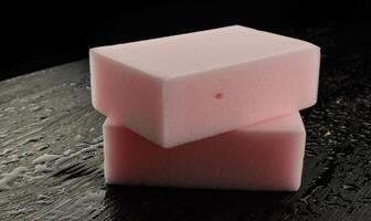 Melamine sponge on a black wet background. Beautiful drops of water around a melamine sponge. photo